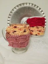 Load image into Gallery viewer, Sometimes you just need that warm drink in your favorite mug! Keep it warmer longer with a Mug Hug. These hand-knitted cozies will fit most standard size mugs. The embroidered style comes with two buttons, making it adjustable for several sizes, and the hand embroidered designs are one-of-a-kind. $5 each  Have a favorite color? Contact Cozy Up for custom orders at CozyUpByClaire@gmail.com! We'll be happy to work with you